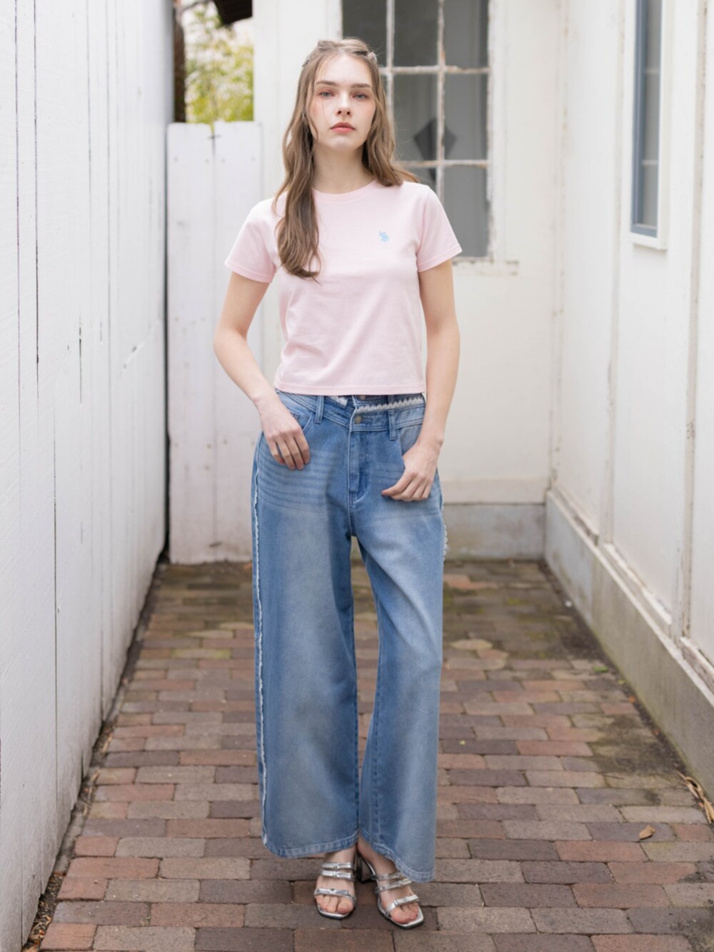 ブルー系のデニムパンツ、シルバー系のサンダル、ピンク系のTシャツ/カットソーを着用したレディースの夏コーディネートの2枚目の写真
