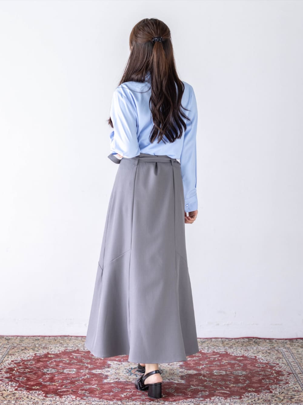 ブラック系のパンプス、グレー系のスカート、ブルー系のシャツ/ブラウスを着用したレディースの夏コーディネートの3枚目の写真