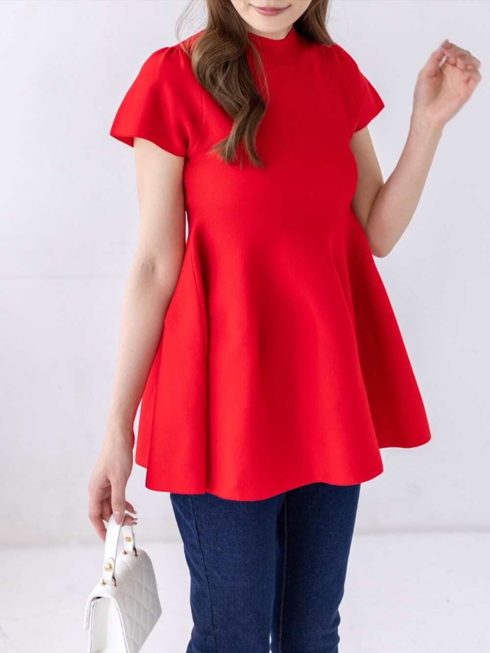 ブルー系のデニムパンツ、ホワイト系のパンプス、レッド系のニット/セーターを着用したレディースの春コーディネートの5枚目の写真