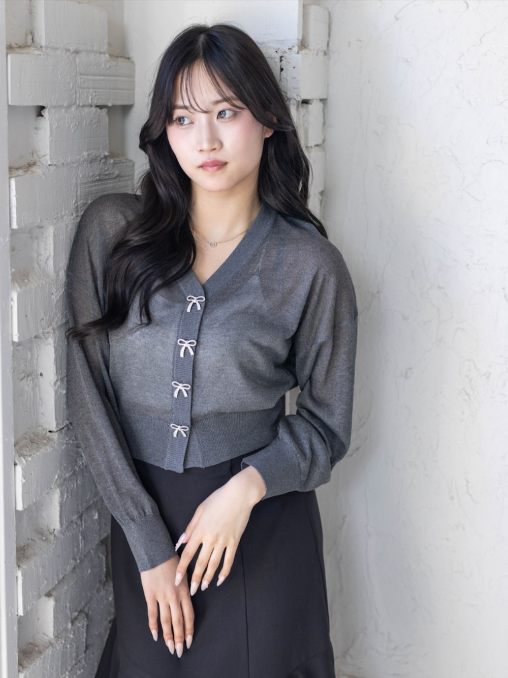 ブラック系のパンプス、ブラック系のスカート、グレー系のカーディガン/ボレロを着用したレディースの春コーディネートの3枚目の写真