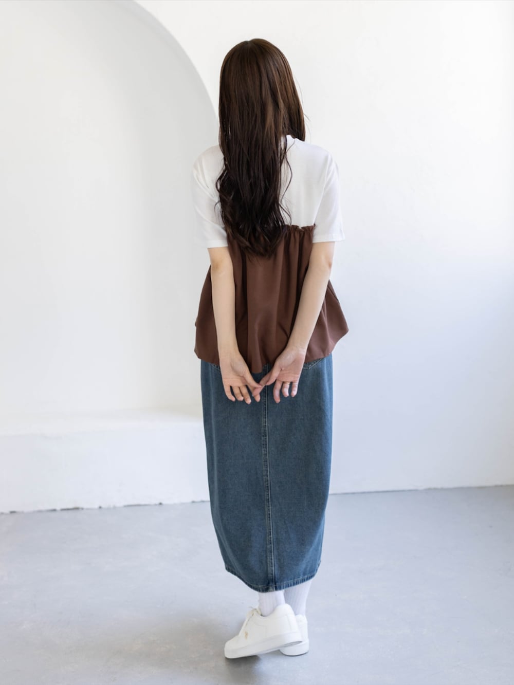 ブルー系のデニムスカート、ゴールド系のスニーカー、ブラウン系のTシャツ/カットソーを着用したレディースの夏コーディネートの2枚目の写真