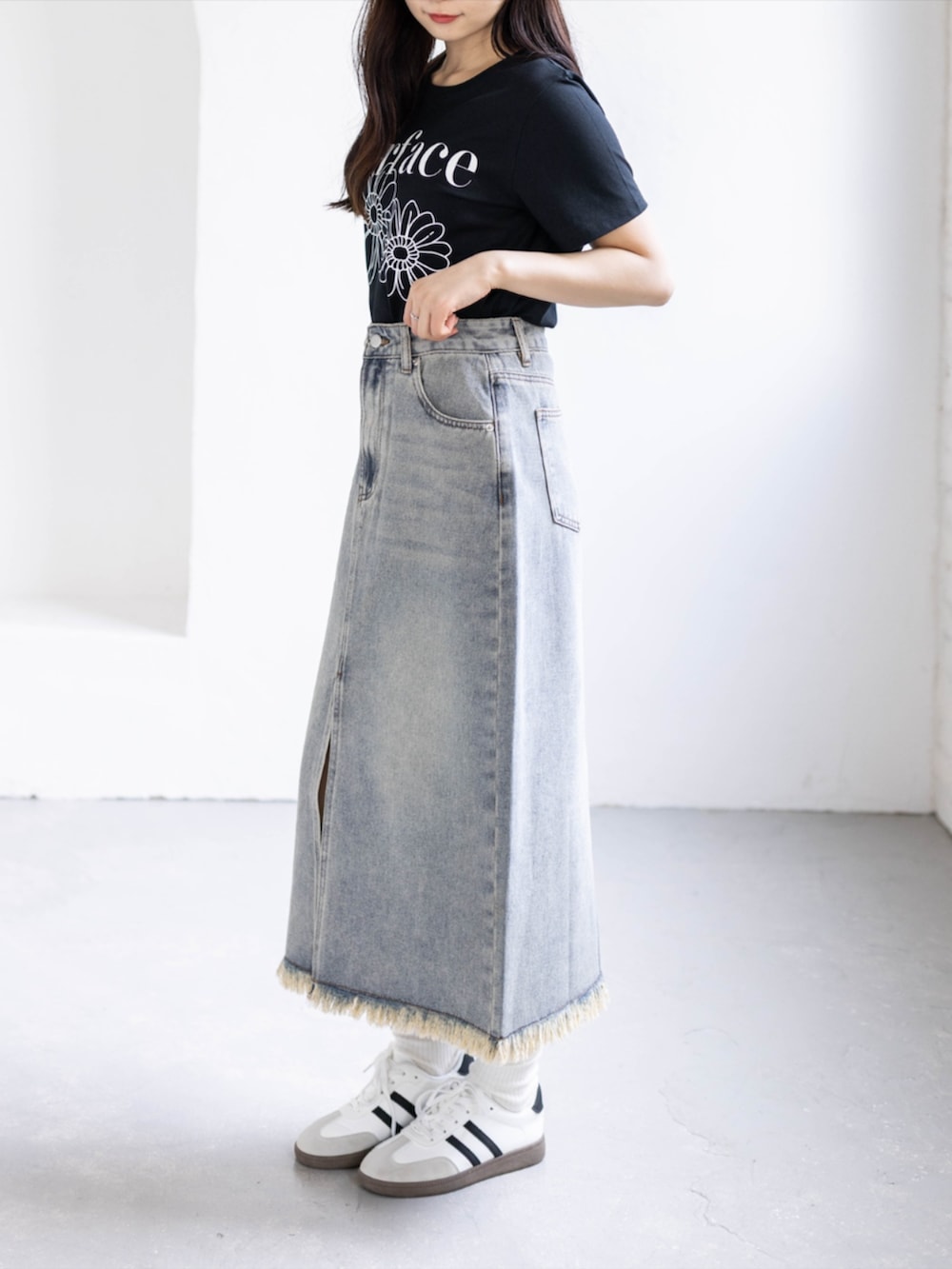 ホワイト系のスニーカー、ブルー系のスカート、ブラック系のTシャツ/カットソーを着用したレディースの春コーディネートの3枚目の写真