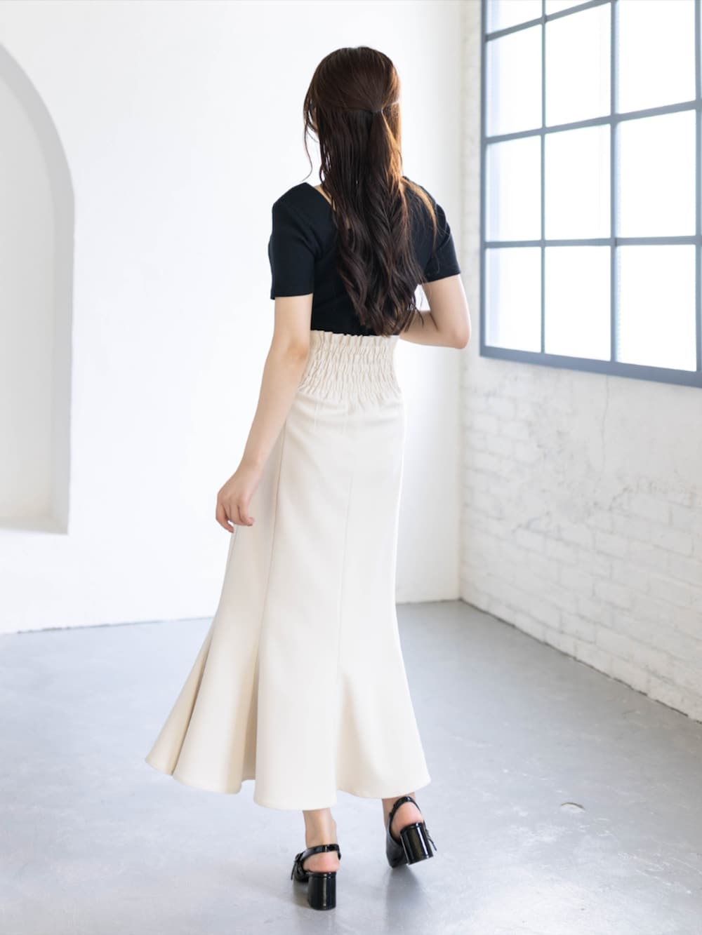 ブラック系のパンプス、ホワイト系のスカート、ブラック系のTシャツ/カットソーを着用したレディースの夏コーディネートの2枚目の写真