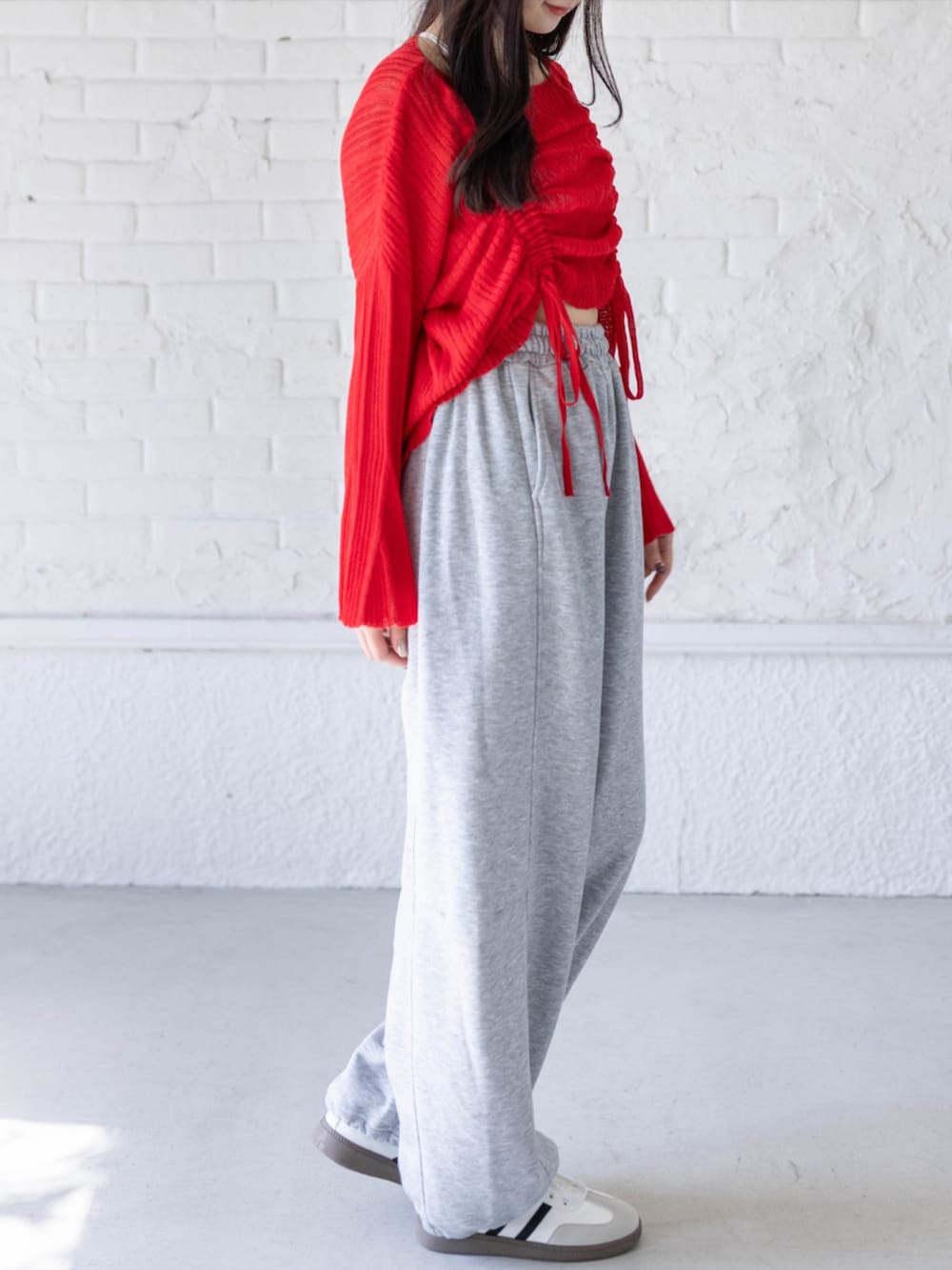 ホワイト系のスニーカー、グレー系のスウェットパンツ、レッド系のニット/セーターを着用したレディースの春コーディネートの3枚目の写真