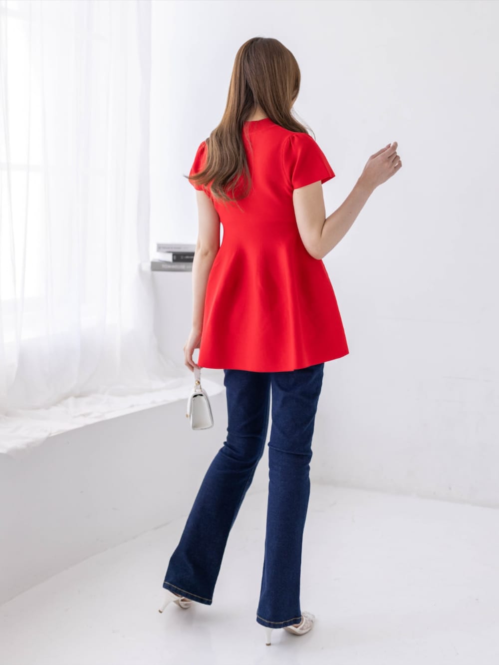 ブルー系のデニムパンツ、ホワイト系のパンプス、レッド系のニット/セーターを着用したレディースの春コーディネートの2枚目の写真