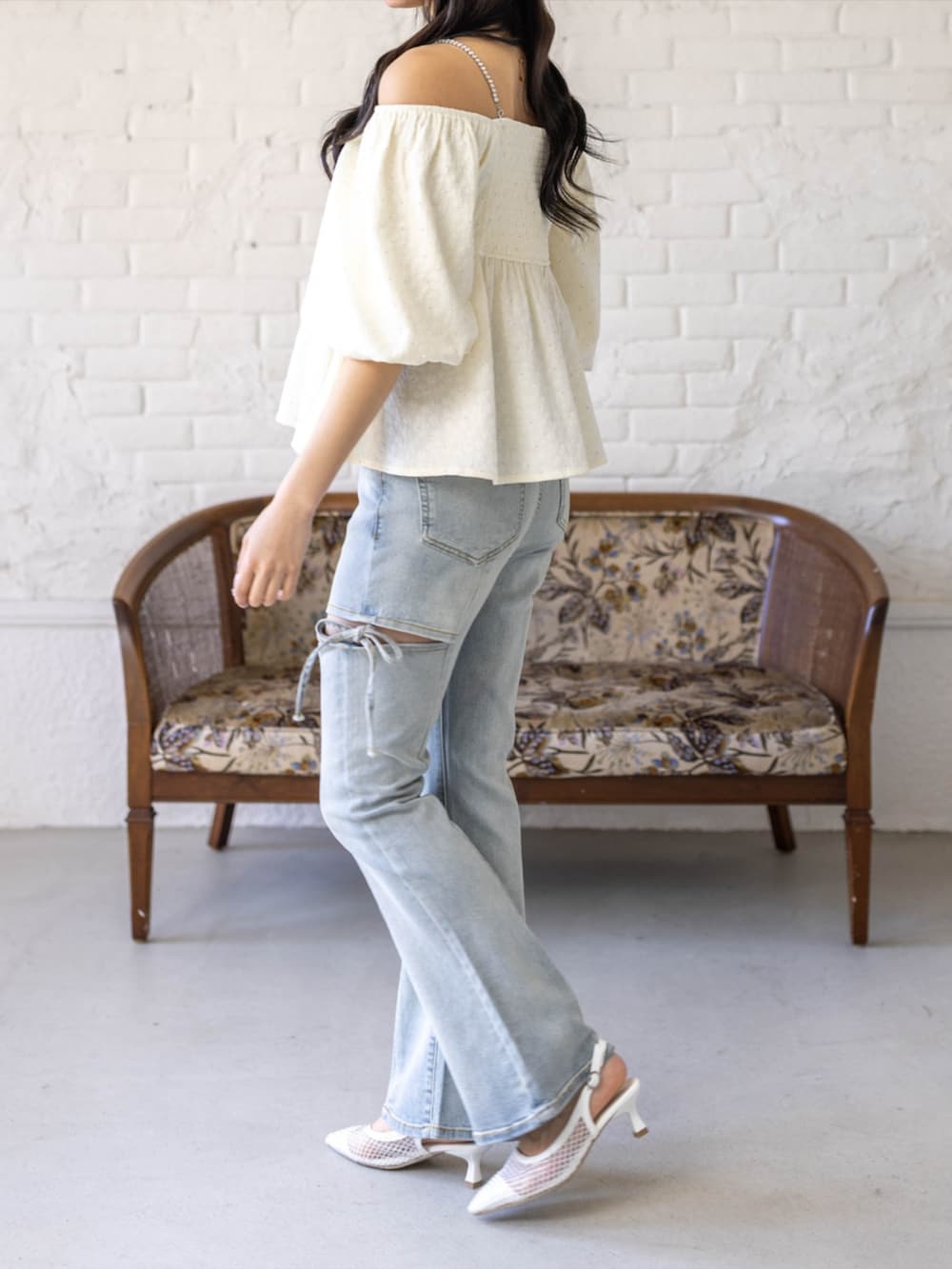 シルバー系のハンドバッグ、ホワイト系のパンプス、ブルー系のデニムパンツを着用したレディースの春コーディネートの3枚目の写真