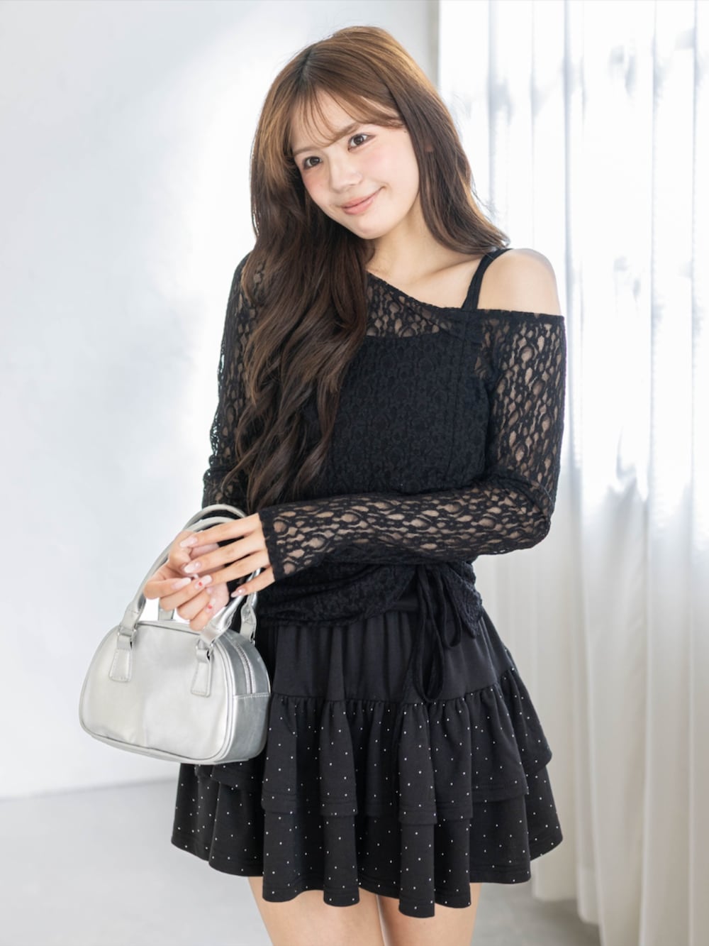 シルバー系のハンドバッグ、ブラック系のアンサンブル、ブラック系のスカートを着用したレディースの春コーディネートの3枚目の写真