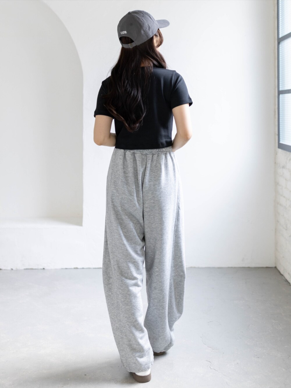 ホワイト系のスニーカー、グレー系のスウェットパンツ、ブラック系のTシャツ/カットソーを着用したレディースの夏コーディネートの2枚目の写真