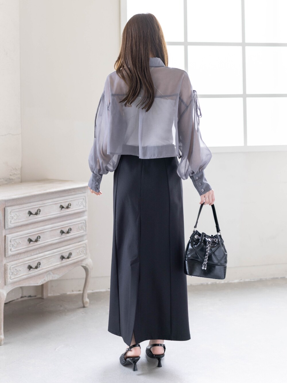 ブラック系のハンドバッグ、ブラック系のパンプス、ブラック系のスカートを着用したレディースの春コーディネートの2枚目の写真