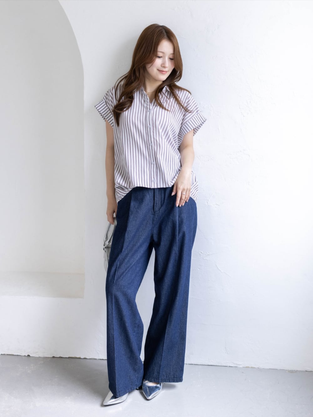 シルバー系のパンプス、ベージュ系のシャツ/ブラウス、ブルー系のデニムパンツを着用したレディースの夏コーディネートの3枚目の写真