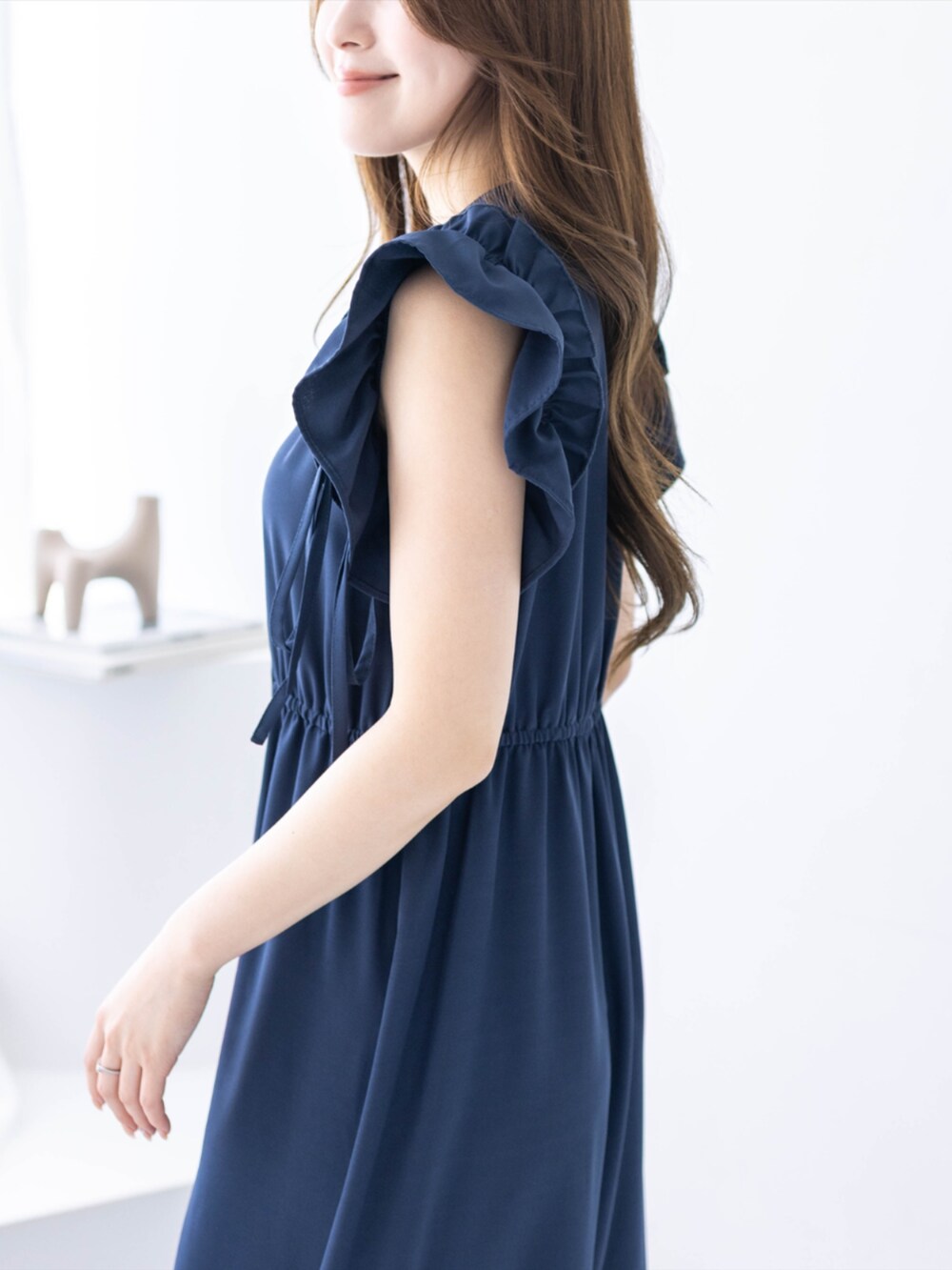 ブラック系のハンドバッグ、ブラック系のパンプス、ブルー系のワンピースを着用したレディースの春コーディネートの4枚目の写真