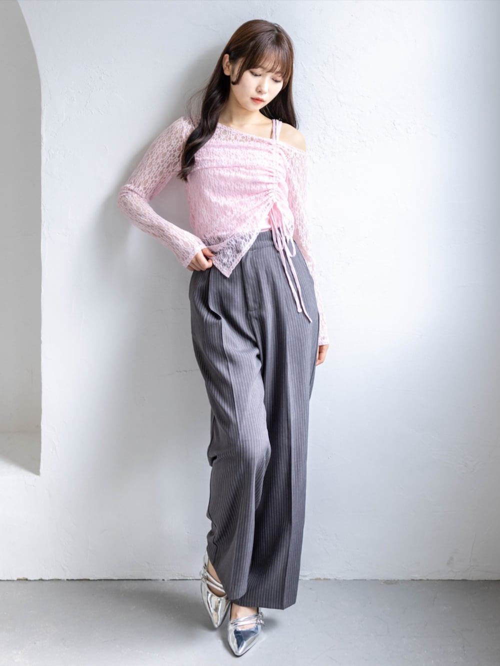 シルバー系のパンプス、グレー系のスラックス、ピンク系のアンサンブルを着用したレディースの春コーディネートの2枚目の写真