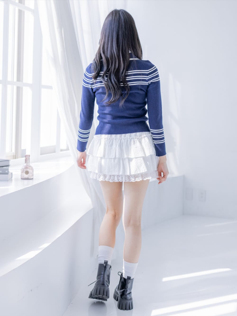 ブラック系のブーツ、ホワイト系のスカート、ブルー系のニット/セーターを着用したレディースの夏コーディネートの4枚目の写真