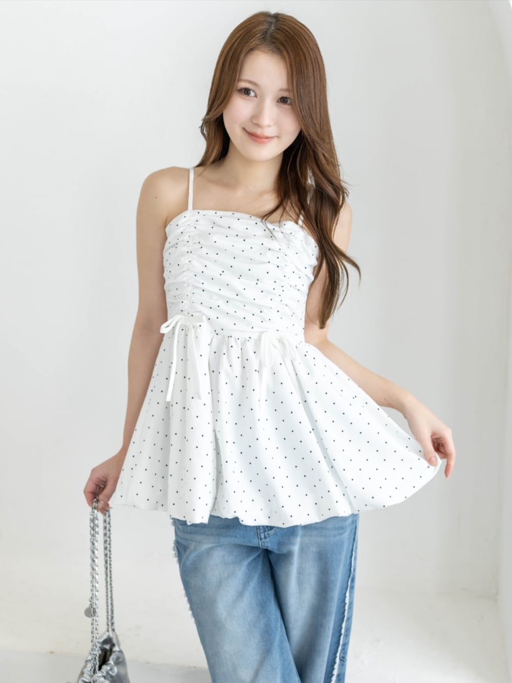 シルバー系のパンプス、ホワイト系のチュニック、ブルー系のデニムパンツを着用したレディースの春コーディネートの3枚目の写真