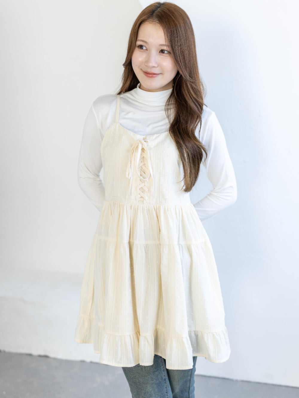 ブルー系のデニムパンツ、ホワイト系のTシャツ/カットソー、ベージュ系のワンピースを着用したレディースの春コーディネートの3枚目の写真