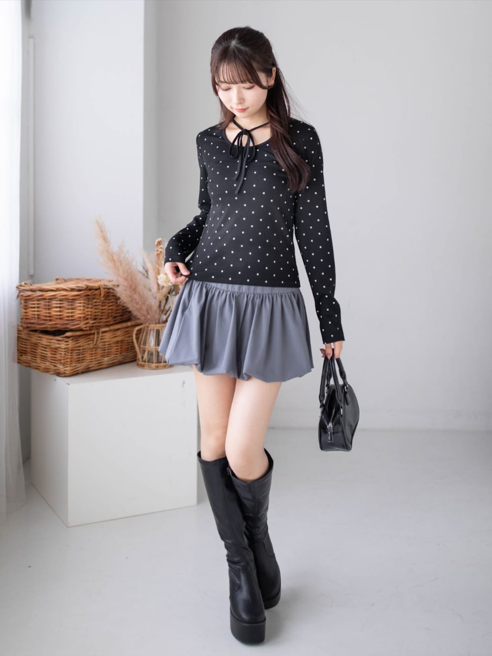 グレー系のスカート、ブラック系のブーツ、ブラック系のTシャツ/カットソーを着用したレディースの秋コーディネートの4枚目の写真
