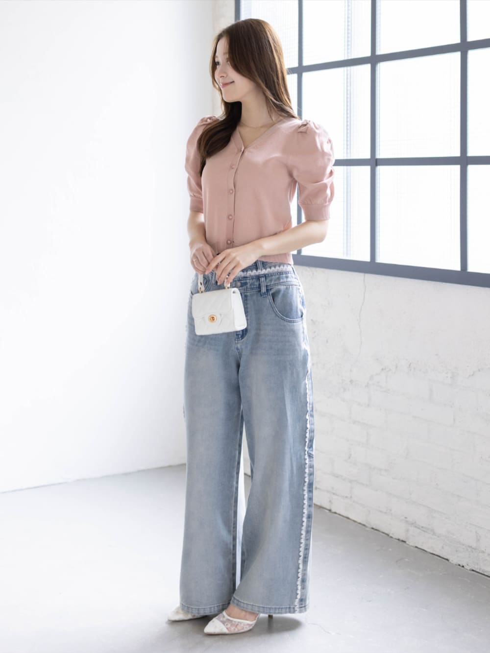 ブルー系のデニムパンツ、ホワイト系のパンプス、ピンク系のカーディガン/ボレロを着用したレディースの春コーディネートの2枚目の写真