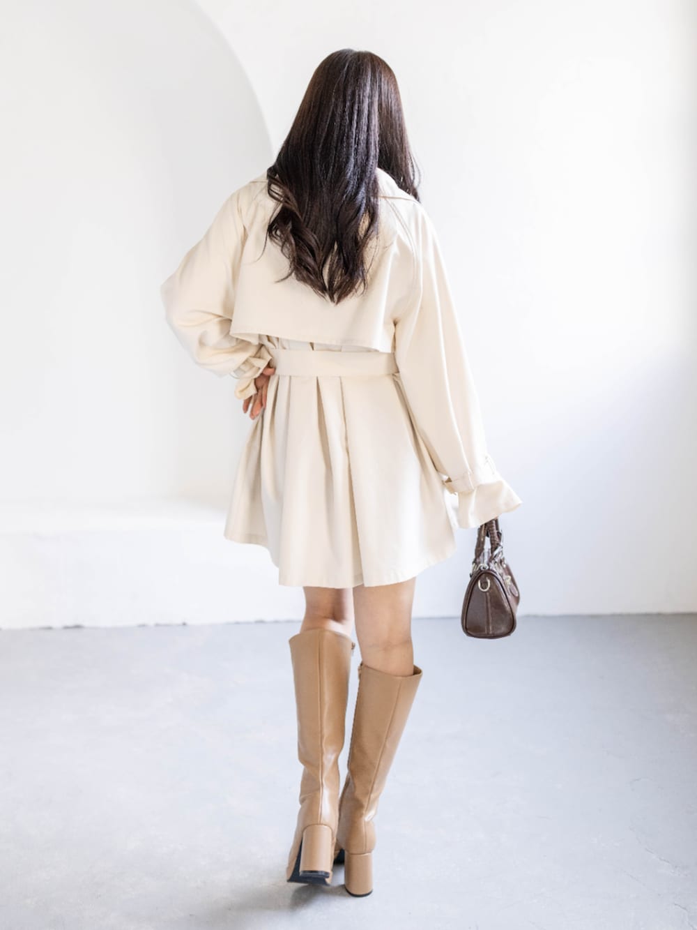 ベージュ系のブーツ、ホワイト系のトレンチコート、ホワイト系のニット/セーターを着用したレディースの春コーディネートの3枚目の写真
