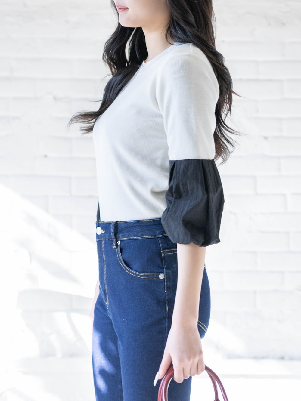 ブラック系のパンプス、ホワイト系のニット/セーター、ブルー系のデニムパンツを着用したレディースの春コーディネートの6枚目の写真