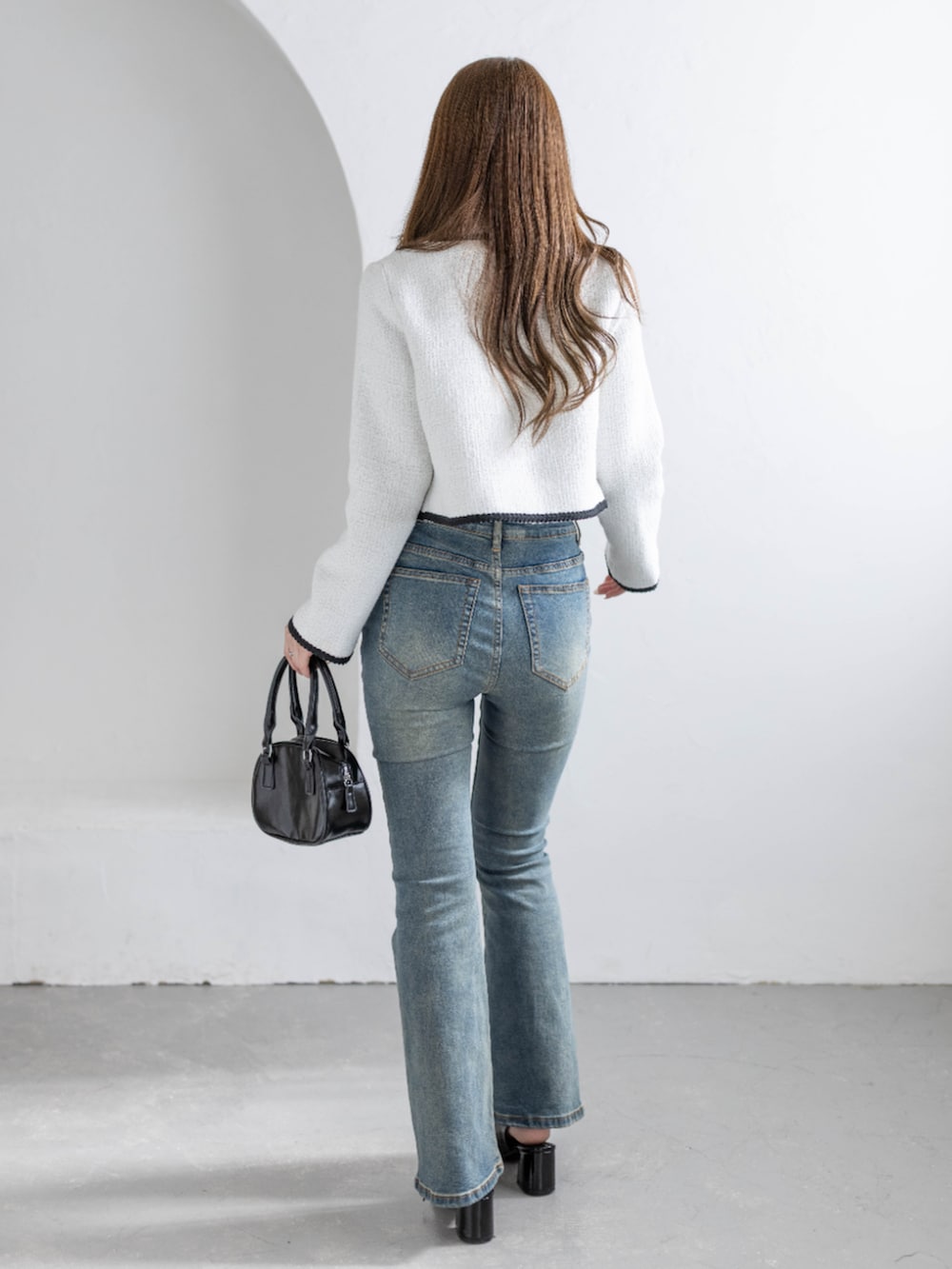 ブルー系のデニムパンツ、ブラック系のパンプス、ホワイト系のノーカラージャケットを着用したレディースの冬コーディネートの2枚目の写真