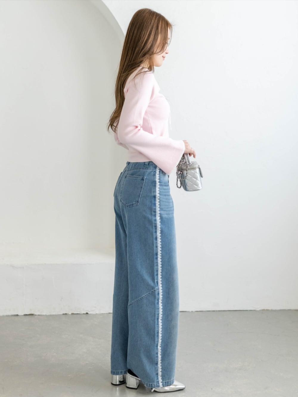 シルバー系のパンプス、ブルー系のデニムパンツ、ピンク系のニット/セーターを着用したレディースの夏コーディネートの3枚目の写真