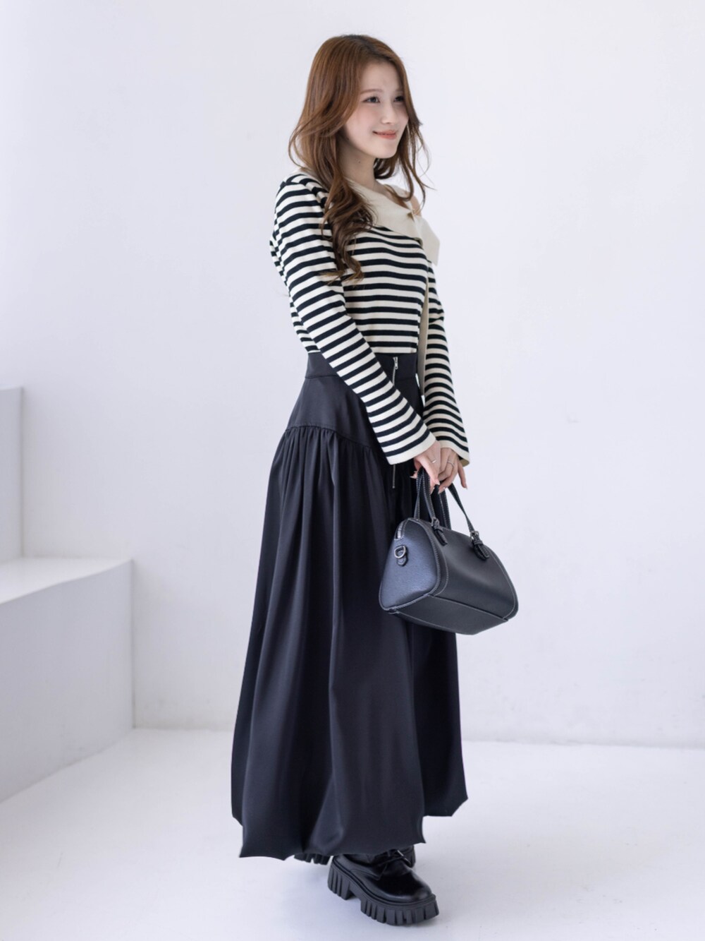 ブラック系のブーツ、ホワイト系のニット/セーター、ブラック系のスカートを着用したレディースの冬コーディネートの3枚目の写真