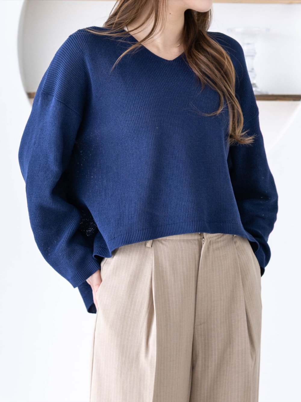 ホワイト系のスニーカー、ベージュ系のスラックス、ブルー系のニット/セーターを着用したレディースの春コーディネートの3枚目の写真