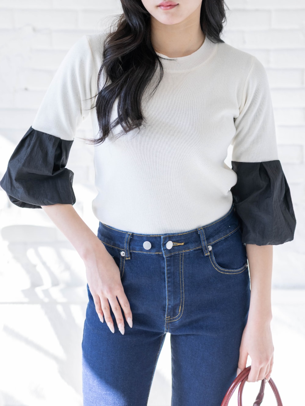 ブラック系のパンプス、ホワイト系のニット/セーター、ブルー系のデニムパンツを着用したレディースの春コーディネートの4枚目の写真