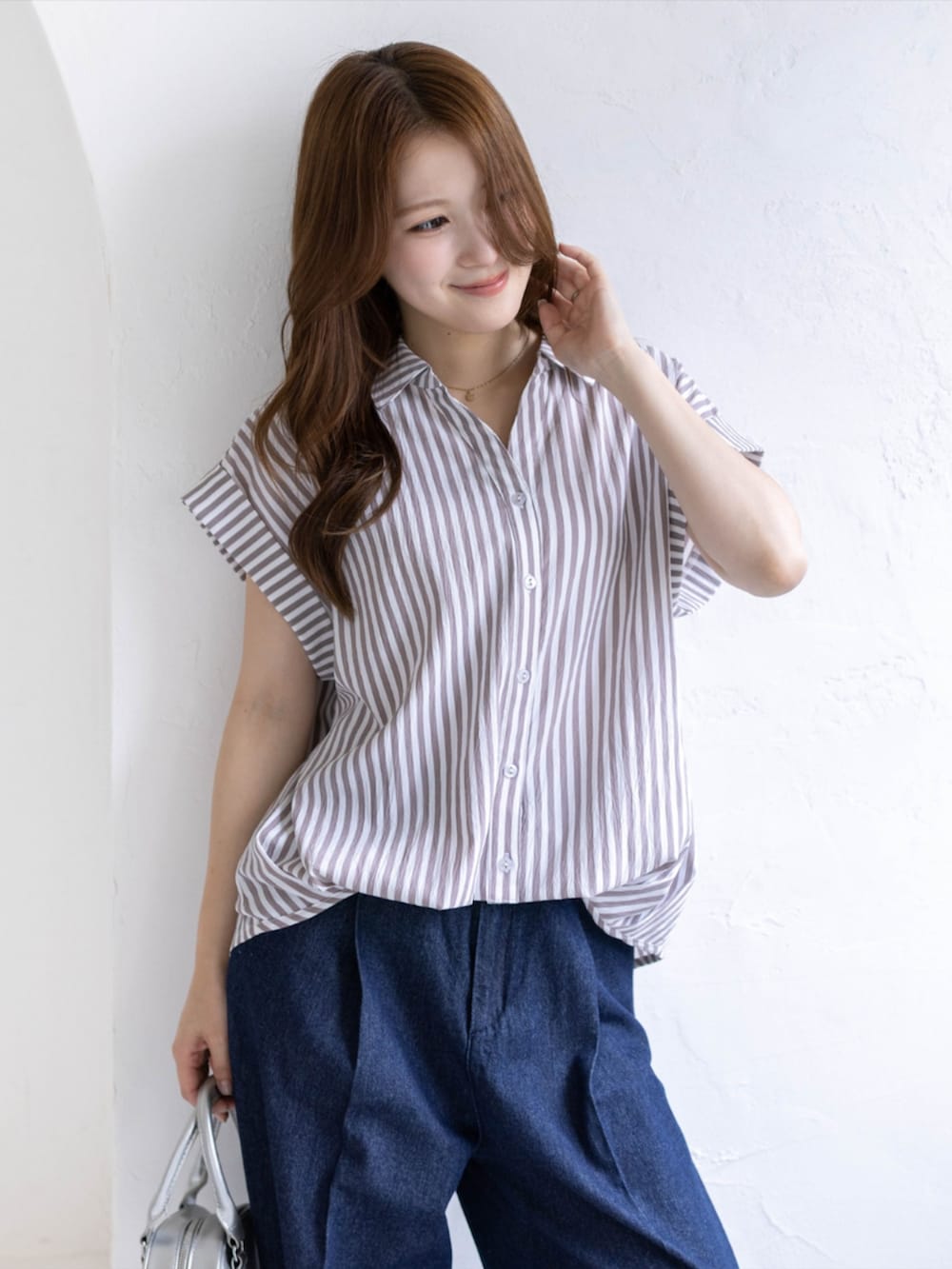 シルバー系のパンプス、ベージュ系のシャツ/ブラウス、ブルー系のデニムパンツを着用したレディースの夏コーディネートの5枚目の写真
