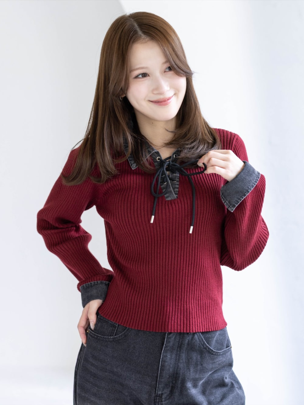 ブラック系のデニムパンツ、ブラック系のブーツ、レッド系のニット/セーターを着用したレディースの秋コーディネートの2枚目の写真
