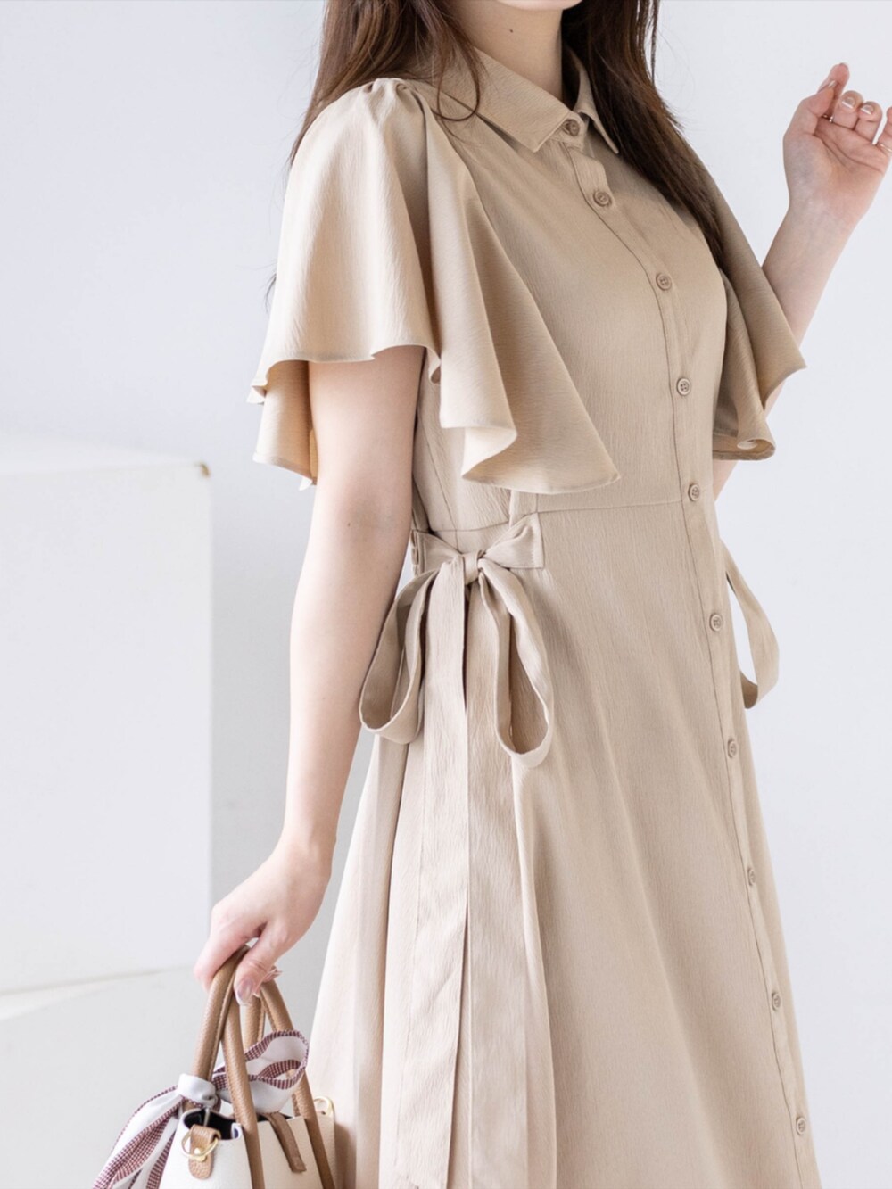 ホワイト系のパンプス、ベージュ系のワンピース、ベージュ系のハンドバッグを着用したレディースの夏コーディネートの5枚目の写真