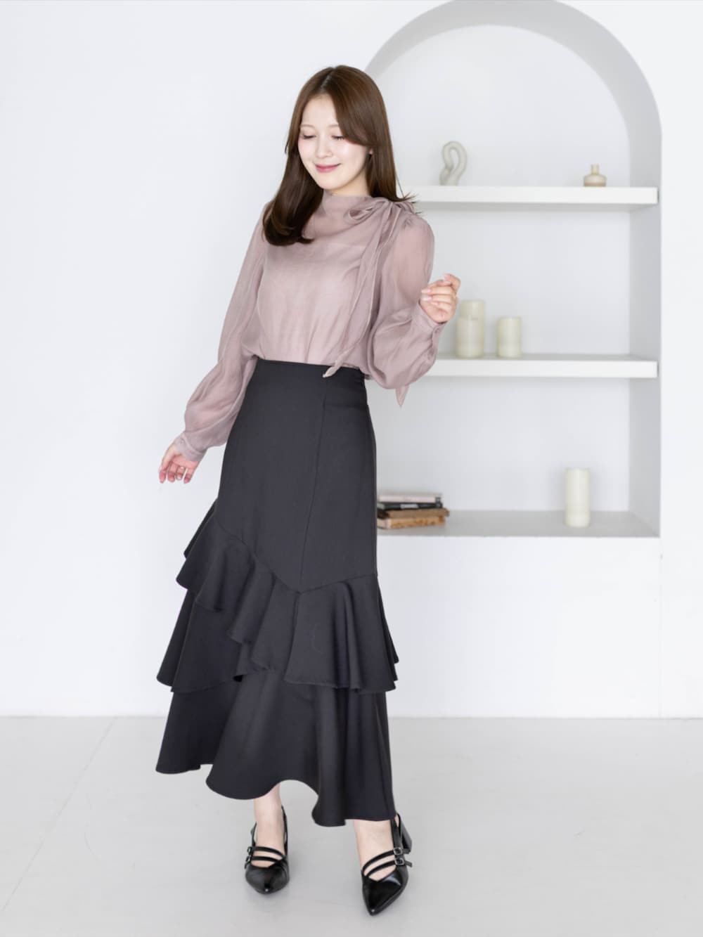 ブラック系のパンプス、ブラック系のスカート、ピンク系のシャツ/ブラウスを着用したレディースの夏コーディネートの2枚目の写真