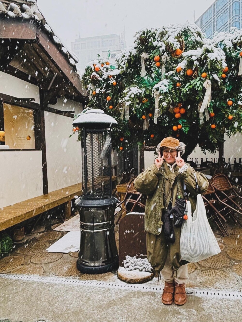 グリーン系のジャケット/アウター、ブラウン系のブーツ、ホワイト系のバッグを着用したレディースの冬コーディネートの4枚目の写真