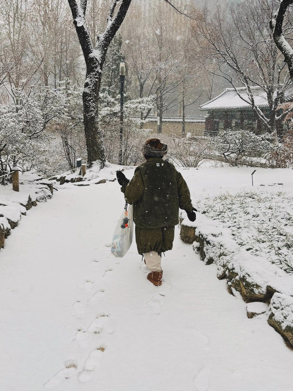 グリーン系のジャケット/アウター、ブラウン系のブーツ、ホワイト系のバッグを着用したレディースの冬コーディネートの5枚目の写真