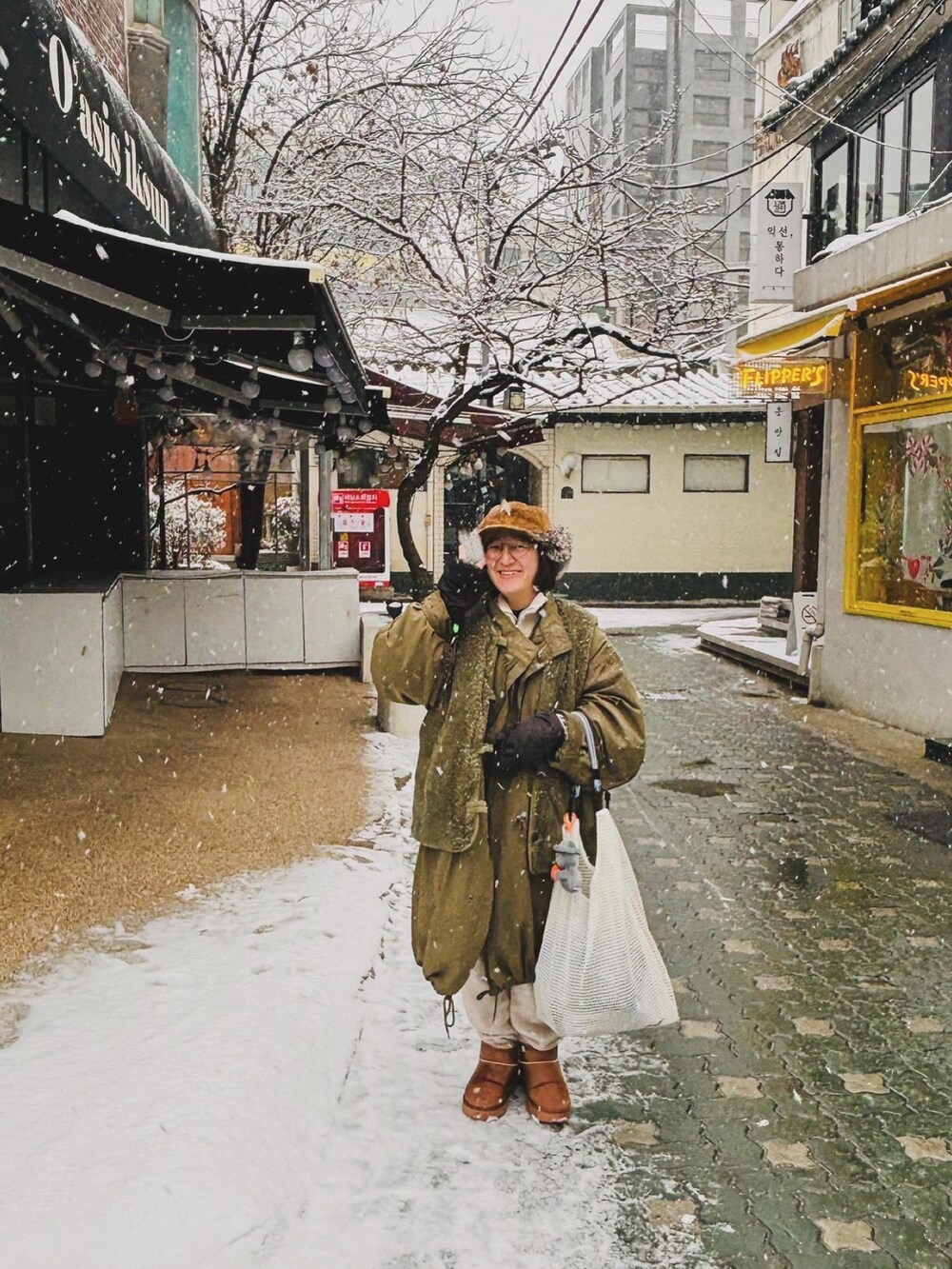 グリーン系のジャケット/アウター、ブラウン系のブーツ、ホワイト系のバッグを着用したレディースの冬コーディネートの3枚目の写真