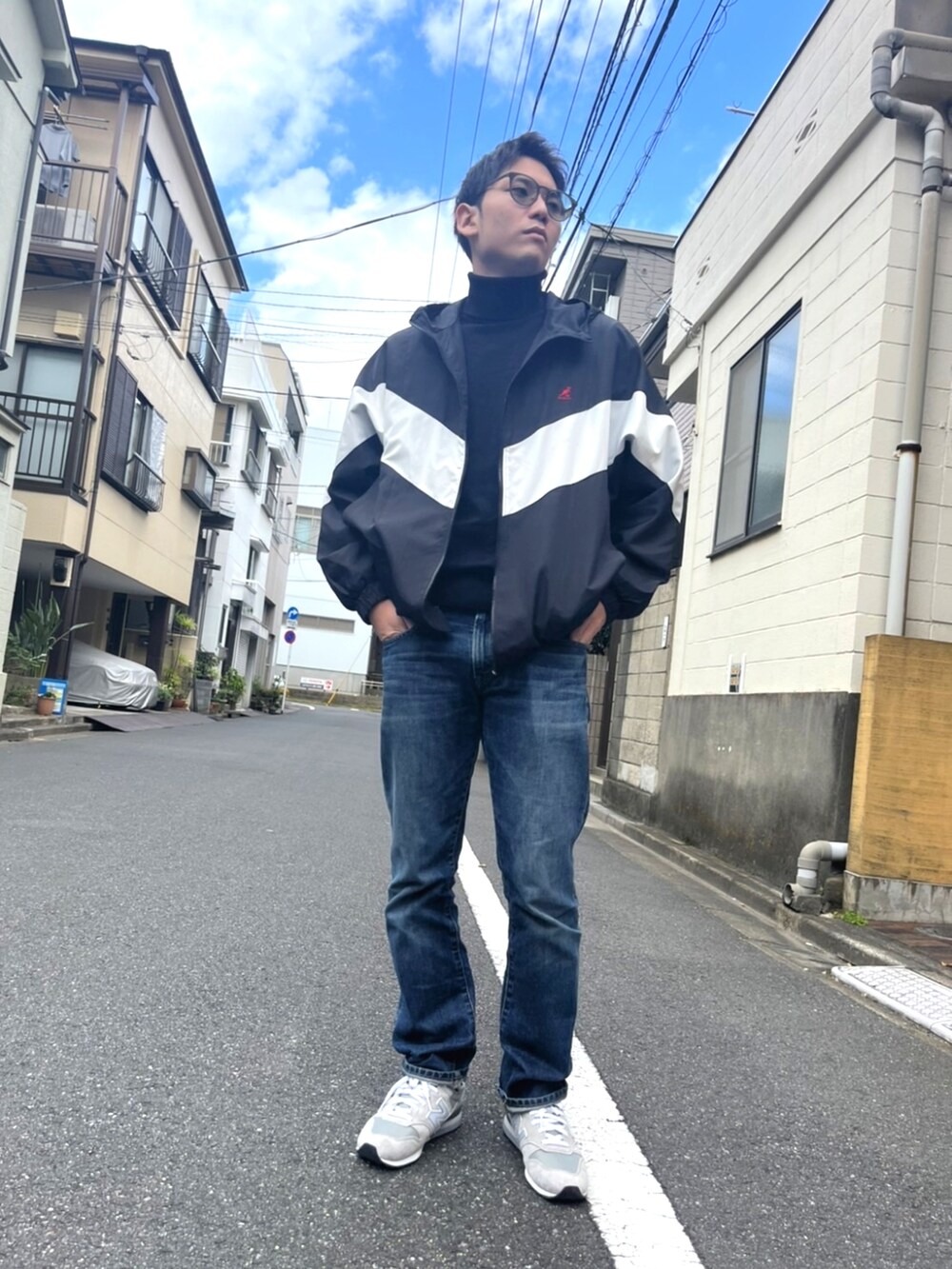 ブラック系のナイロンジャケット、ブルー系のデニムパンツ、グレー系のスニーカーを着用したメンズの秋コーディネートの2枚目の写真