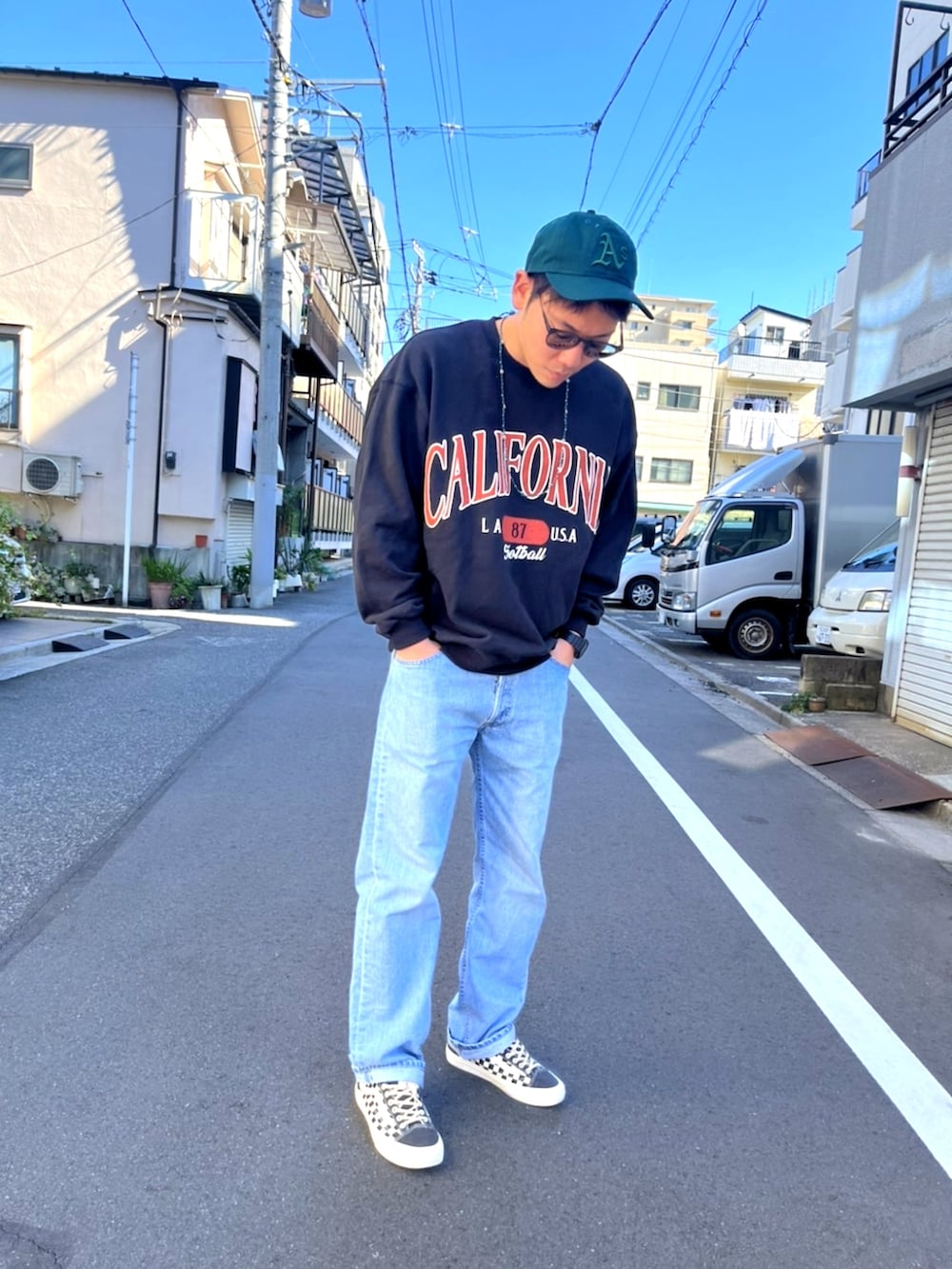 ブルー系のデニムパンツ、ブラック系のスウェット、ブラック系のスニーカーを着用したメンズの秋コーディネートの2枚目の写真