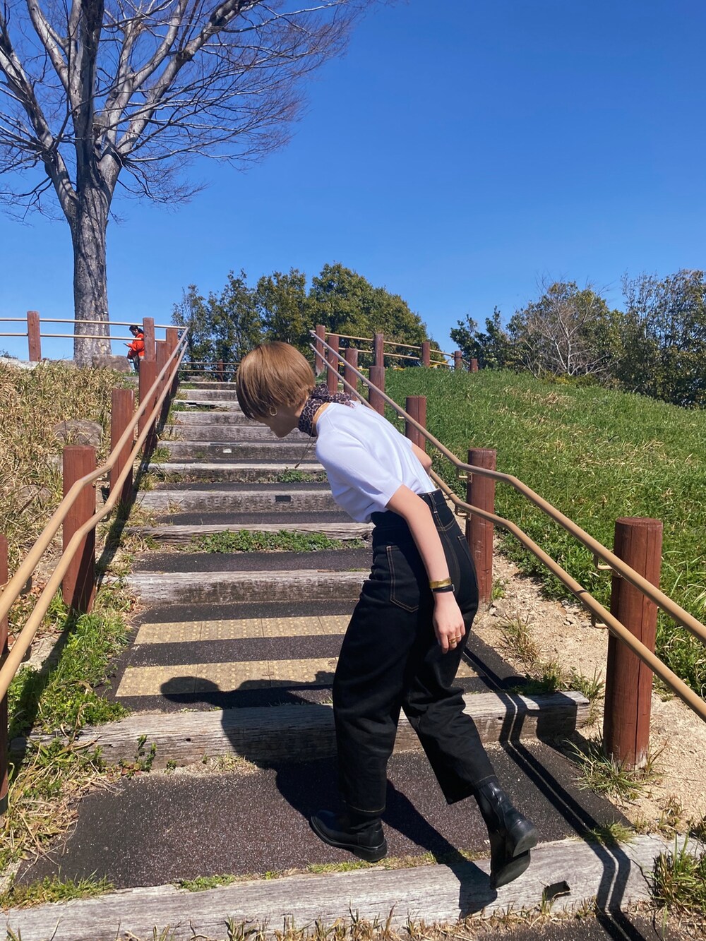 ブラック系のデニムパンツ、ブラック系のブーツ、ホワイト系のニット/セーターを着用したレディースの春コーディネートの2枚目の写真