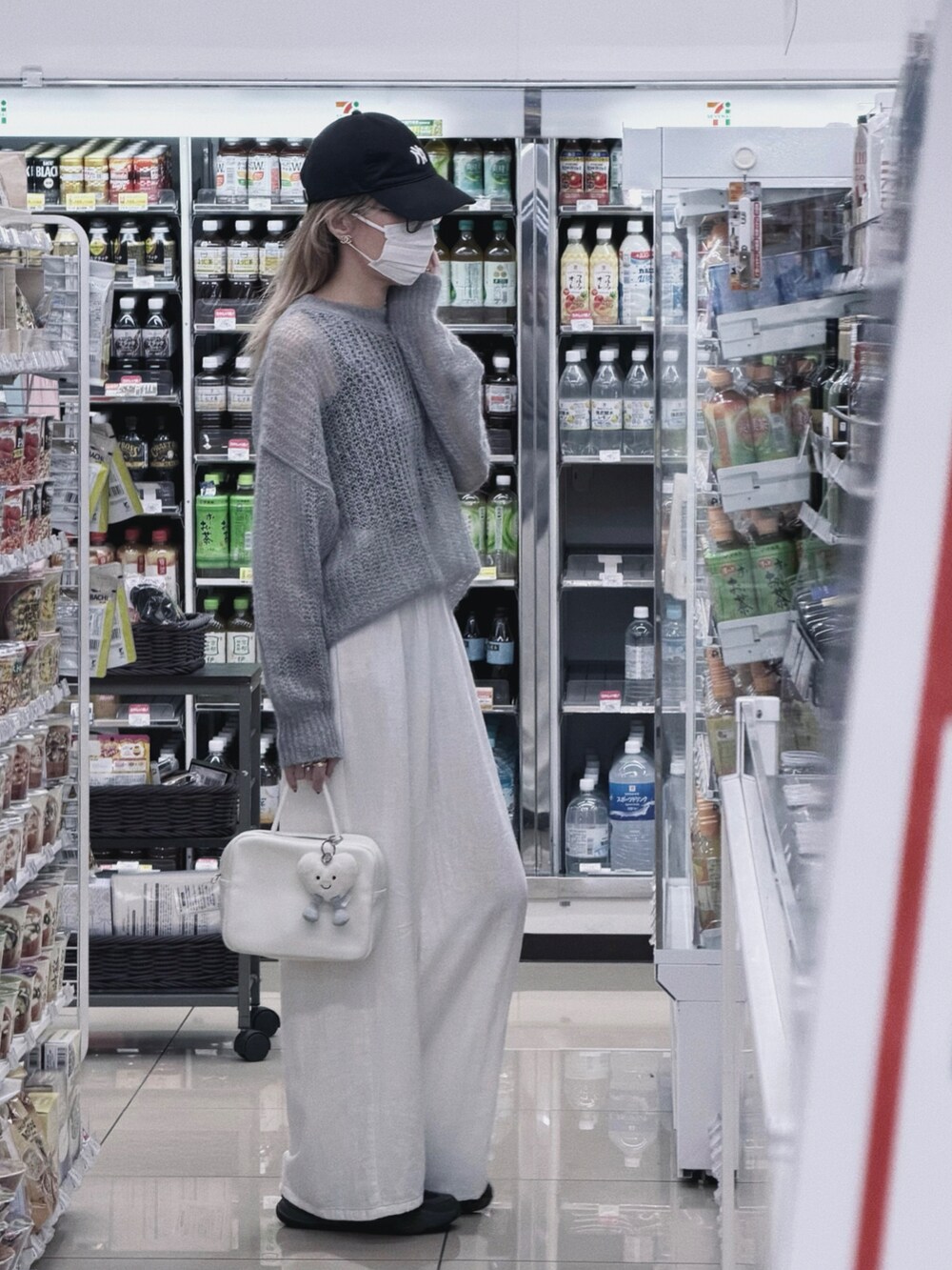 グレー系のニット/セーター、ホワイト系のパンツ、ホワイト系のバッグを着用したレディースの秋コーディネートの2枚目の写真