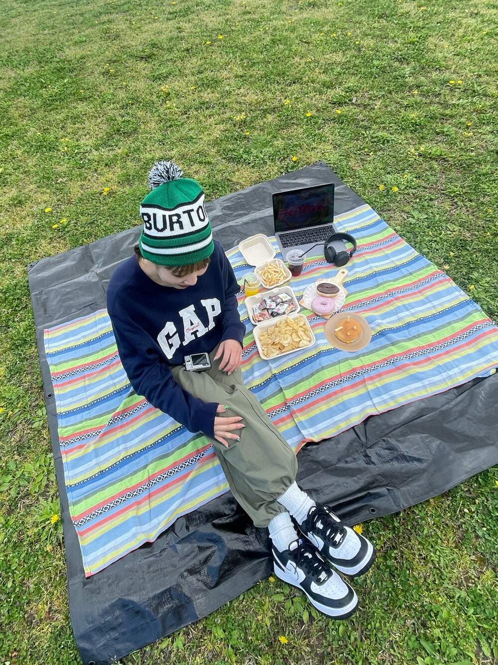 ブルー系のスウェット、グリーン系のカーゴパンツ、ホワイト系のスニーカーを着用したレディースの春コーディネートの2枚目の写真