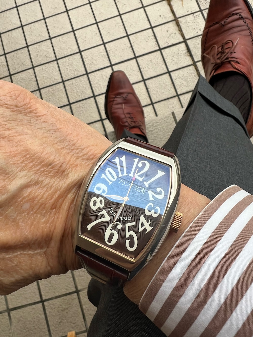 ブラウン系のビジネスシャツ、ブラウン系のネクタイ、ブラウン系のポケットチーフを着用したメンズの春コーディネートの3枚目の写真