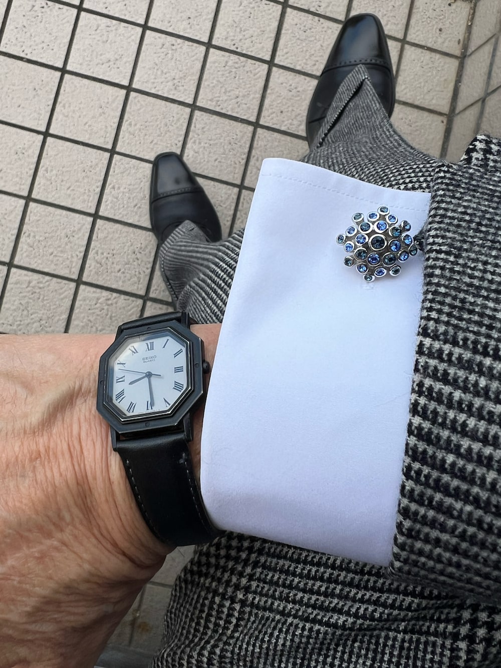 グレー系のスーツジャケット、ブルー系のネクタイ、ブルー系のポケットチーフを着用したメンズの秋コーディネートの2枚目の写真