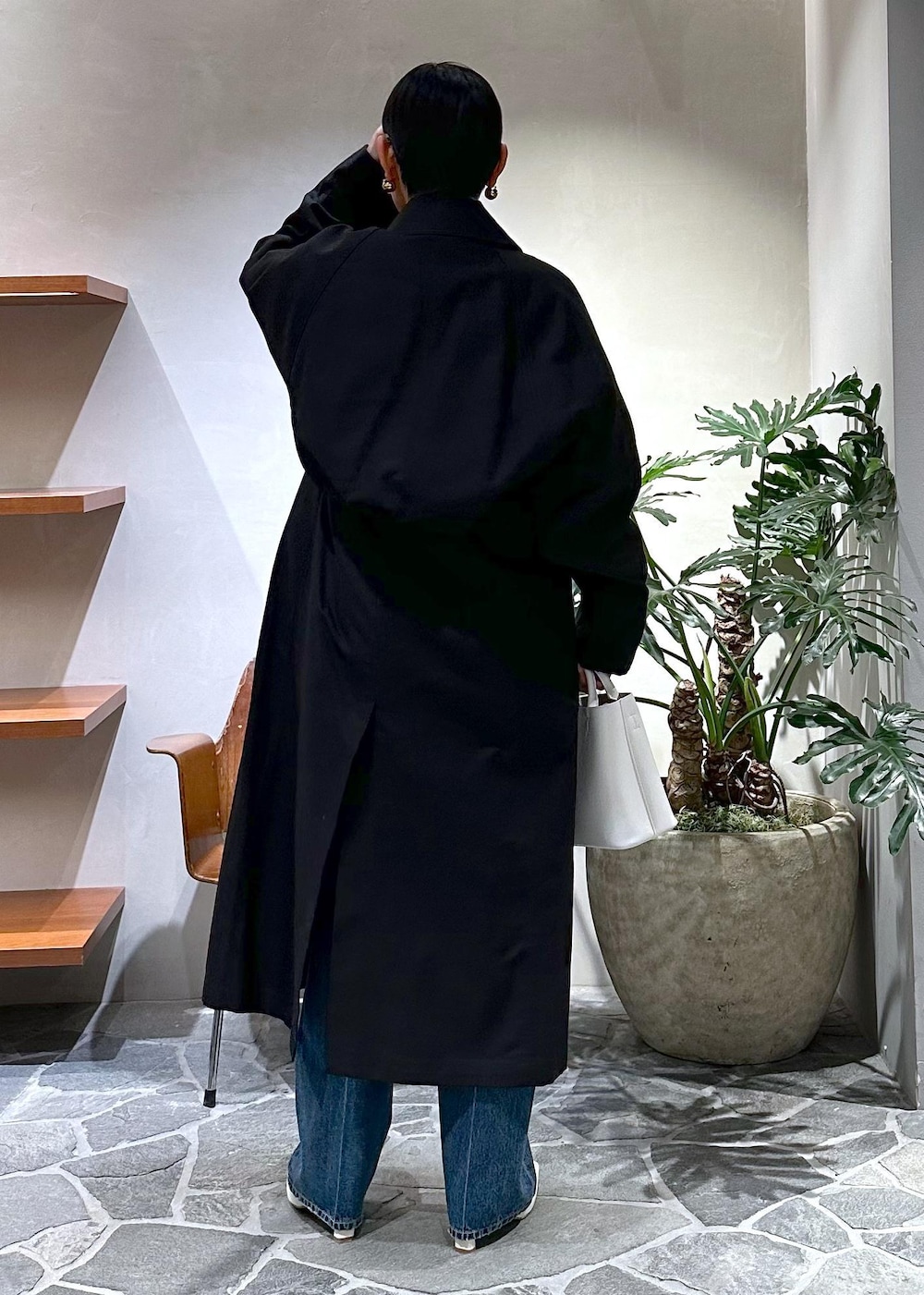 ホワイト系のブーツ、ブラック系のステンカラーコート、ホワイト系のハンドバッグを着用したレディースの冬コーディネートの5枚目の写真