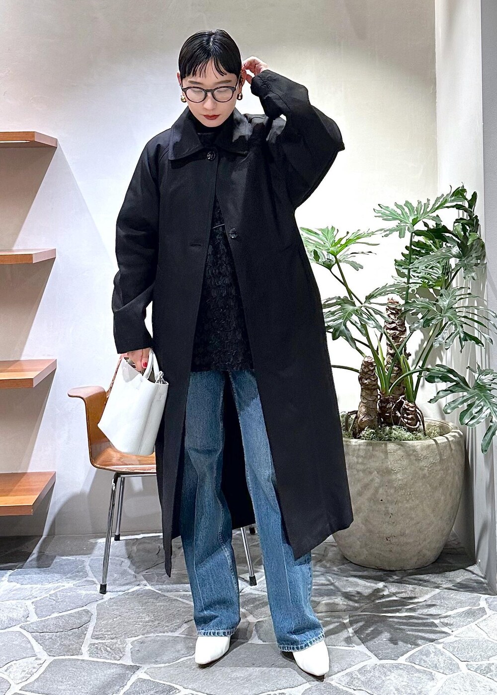 ホワイト系のブーツ、ブラック系のステンカラーコート、ホワイト系のハンドバッグを着用したレディースの冬コーディネートの4枚目の写真