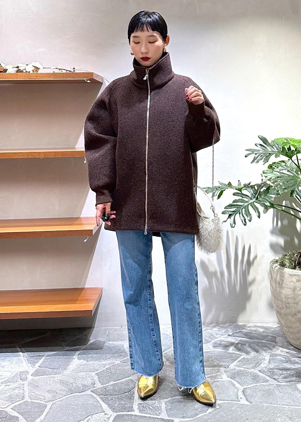 ブルー系のデニムパンツ、ゴールド系のブーツ、ホワイト系のカーディガン/ボレロを着用したレディースの秋コーディネートの5枚目の写真