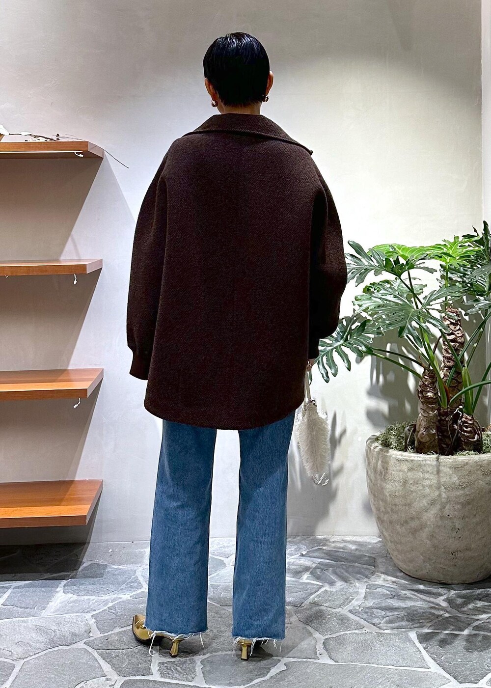 ブルー系のデニムパンツ、ゴールド系のブーツ、ホワイト系のカーディガン/ボレロを着用したレディースの秋コーディネートの3枚目の写真