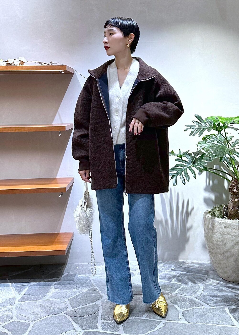 ブルー系のデニムパンツ、ゴールド系のブーツ、ホワイト系のカーディガン/ボレロを着用したレディースの秋コーディネートの4枚目の写真