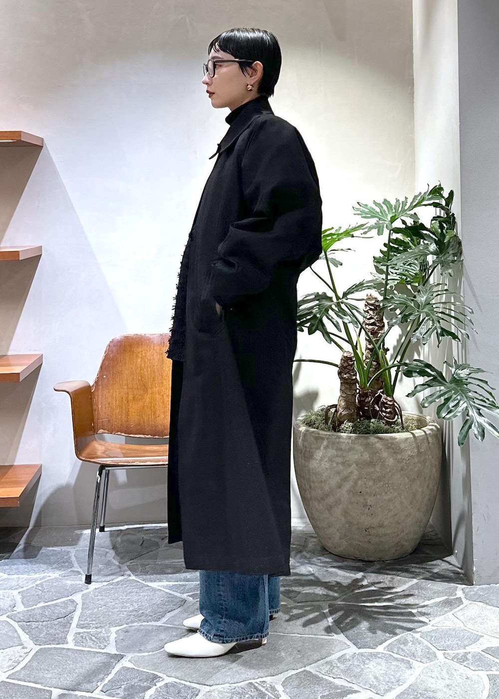 ホワイト系のブーツ、ブラック系のステンカラーコート、ホワイト系のハンドバッグを着用したレディースの冬コーディネートの2枚目の写真