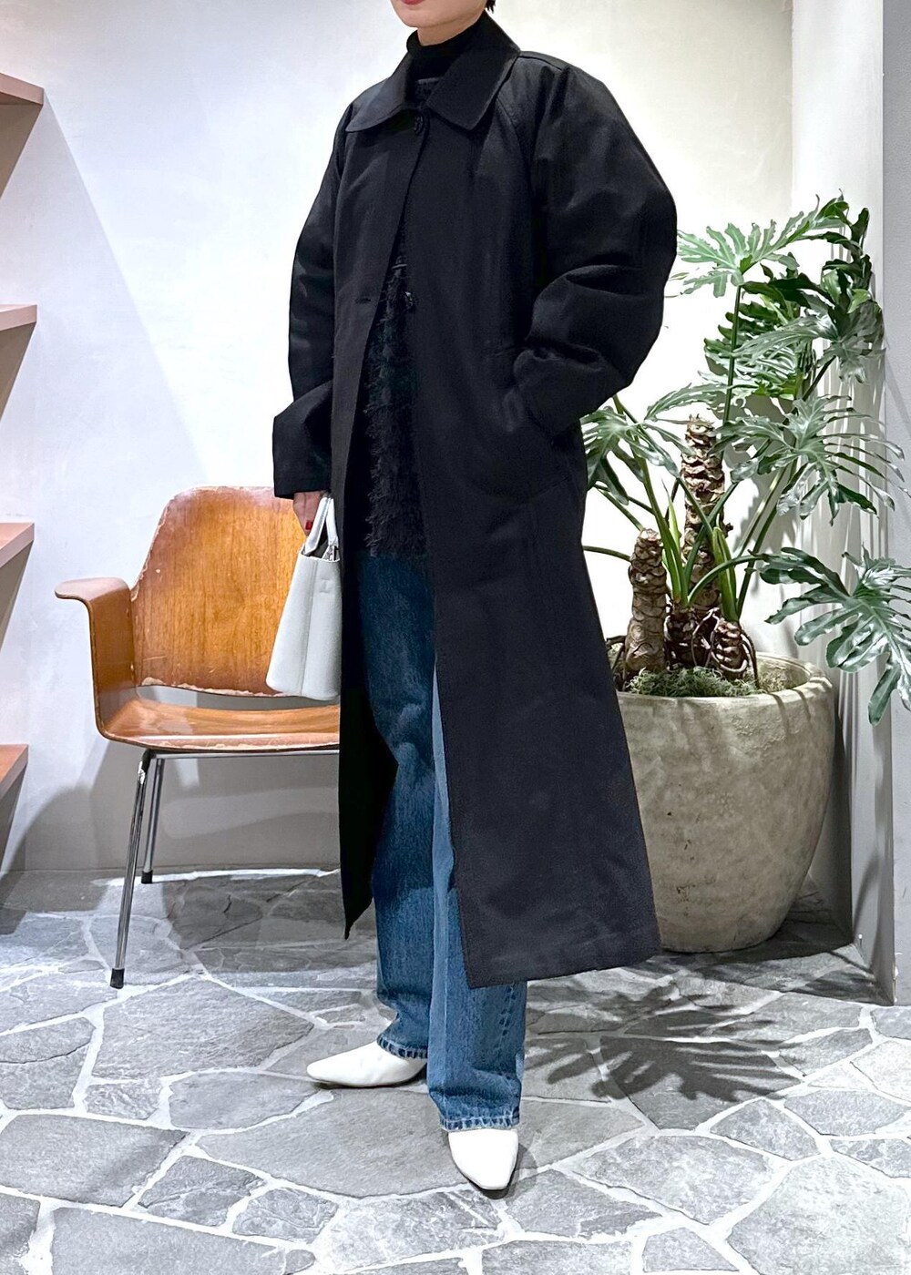 ホワイト系のブーツ、ブラック系のステンカラーコート、ホワイト系のハンドバッグを着用したレディースの冬コーディネートの6枚目の写真