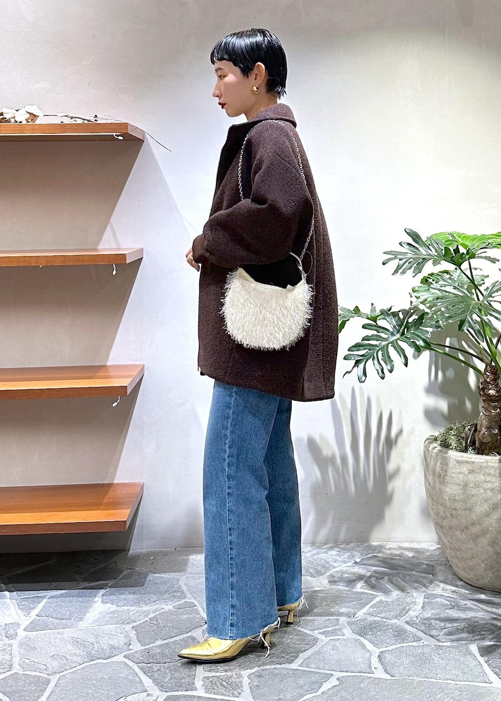 ブルー系のデニムパンツ、ゴールド系のブーツ、ホワイト系のカーディガン/ボレロを着用したレディースの秋コーディネートの2枚目の写真